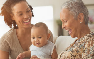 three generations of black women laughing on the couch