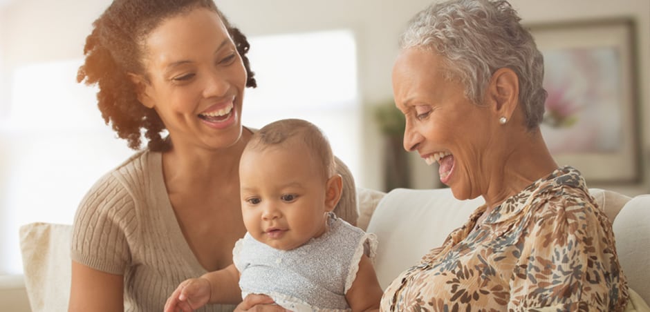 three generations of black women laughing on the couch