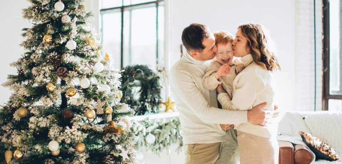 a man woman and child embracing by their christmas tree